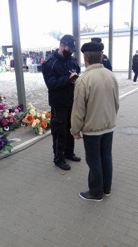 policjant legitymujący mężczyznę na targowisku miejskim