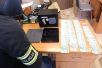 Policjant spisuje banknoty leżące na biurku.