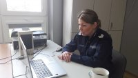 Policjantka siedzi w klasie, przy biurku i on-line prowadzi rozmowę z uczniami