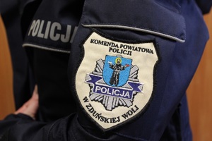 Na rękawie policyjnej kurtki naszywka: Komenda Powiatowa Policji w Zduńskiej Woli.