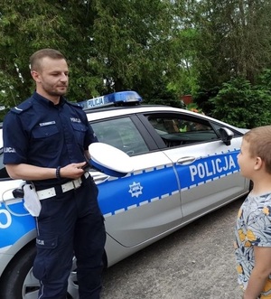 Policjant pokazuje dziecku czapkę policyjną.