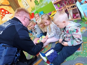 Policjant rozdaje dzieciom odblaski.
