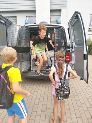 Dzieci wsiadają do radiowozu policyjnego.