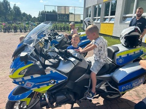 Chłopcy siedzą na policyjnych motocyklach.