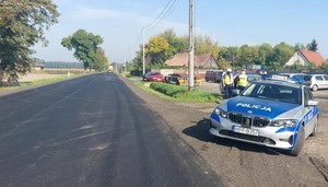 Po prawej stronie zdjęcia stoi oznakowany radiowóz grupy Speed. Policjanci kontrolują kierującego samochodem, który został zatrzymany do kontroli.