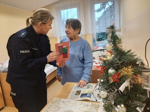 Policjantka wręcza kobiecie świąteczną kartkę