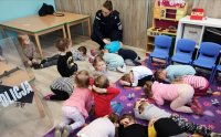 St. sierż. Kamila Sowińska uczy dzieci jak chronić się przed atakiem niebezpiecznego zwierzęcia. Przyjmowanie bezpiecznej pozycji przez przedszkolaków tzw. żółwika.