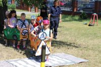 Dzieci pod nadzorem policjantki uczą się prawidłowych zachowań na skrzyżowaniu.