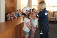 Policjantka pomagająca założyć dzieciom sprzęt służący do zabezpieczeń imprez masowych.