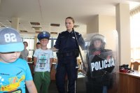 Sierżant sztabowy Kamila Sowińska z dziećmi ubranymi w elementy wyposażenia policjantów.