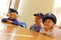 Uśmiechnięte dzieci przymierzają policyjne czapki służbowe,