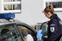 Policjantka prezentuje dzieciom policyjny radiowóz.