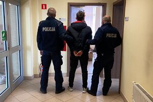 jeden z zatrzymanych mężczyzn w kajdankach w obecności dwóch umundurowanych policjantów