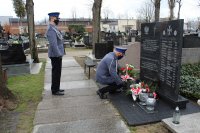 Zastępca Komendanta Powiatowego Policji w Zduńskiej Woli składa kwiaty przy tablicy na cmentarzu