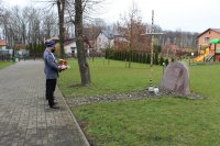 Zastępca Komendanta Powiatowego Policji w Zduńskiej Woli składa kwiaty przy pamiątkowej tablicy przy szkole w Wojsławicach