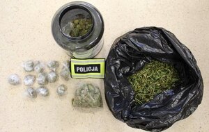 Na podłodze leży duży worek na śmieci, koloru czarnego, pojemnik po odżywkach oraz foliowe woreczki, w których znajduje się marihuana