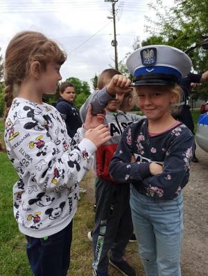 Dziewczynki przymierzają policyjną czapkę.
