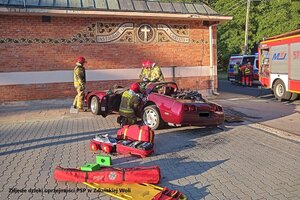 Strażacy podczas pracy przy rozbitym samochodzie.
