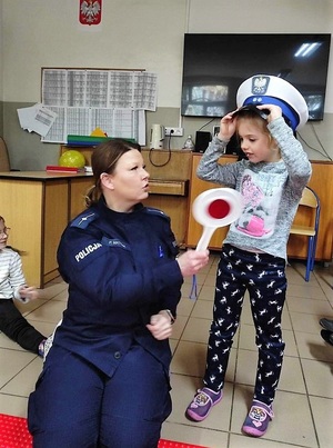 Policjantka pokazuje uczniom wyposażenie funkcjonariusza podczas służby.