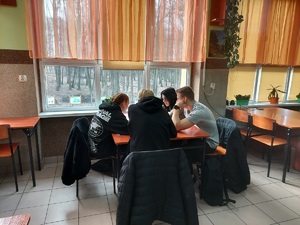 Młodzież siedzi przy stole i rozwiązuje test
