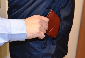 Na zdjęciu widać rękę, która wyciąga portfel z czyjejś kieszeni