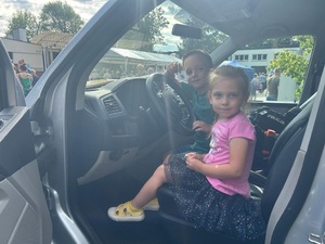 Dziewczynka i chłopiec siedzą za kierownicą radiowozu