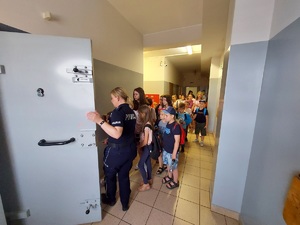 Policjanta pokazuje dzieciom pomieszczenia dla osób zatrzymanych