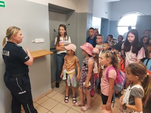 Policjantka pokazuje dzieciom pomieszczenia dla osób zatrzymanych