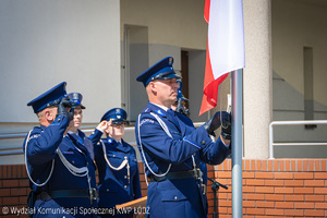 Poczet flagowy salutuje i jeden z policjantów wciąga flagę Polski na maszt.