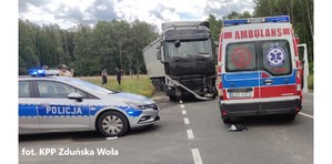 Droga gdzie doszło do wypadku. Na wprost samochód ciężarowy marki Renault koloru czarnego, po prawej stronie karetka pogotowia, a po lewej radiowóz policyjny.