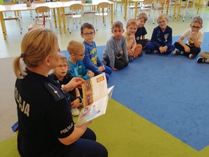 Policjantka czyta dzieciom książkę.