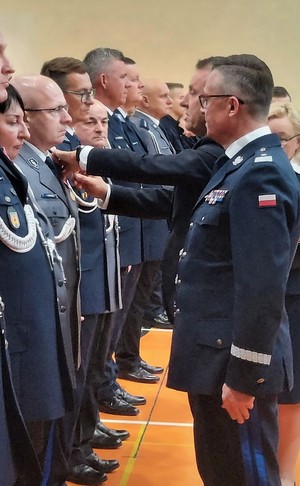 Medal zduńskowolskiemu policjantowi wpina Wojewoda Łódzki Karol Młynarczyk, obok stoi Komendant Wojewódzki Policji w Łodzi.
