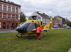 Lotnicze Pogotowie Ratunkowe - helikopter sto na trawniku, przy drzwiach stoi ratownik odwrócony tyłem do zdjęcia.