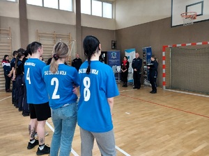 Jedna z drużyn stoi tyłem do zdjęcia, mają jednakowe koszulki z numerami na plecach i nazwą szkoły ZSAS Zduńska Wola