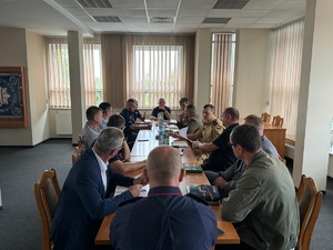 Aula zduńskowolskiej komendy. Przy długim stole, siedzą uczestnicy spotkania. W szczycie stołu siedzi gospodarz - zduńskowolski komendant.