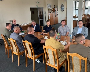 Aula zduńskowolskiej komendy. Przy długim stole, siedzą uczestnicy spotkania.