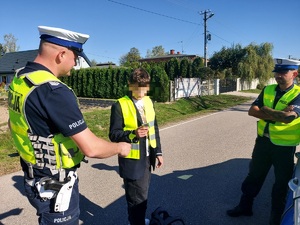 Policjanci dają chłopcu elementy odblaskowe.