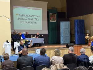 Umundurowana policjantka prezentująca zawartość walizki edukacyjnej, gdzie są imitację środków odurzających.