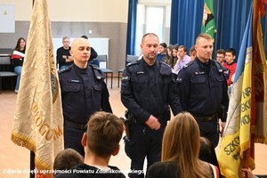 Policjanci pokazują młodzieży jak prowadzić poczet sztandarowy.