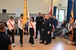 Uczniowie z pocztem ćwiczą przed policjantami.