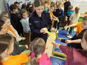 Policjantka rozdaje dzieciom odblaski.