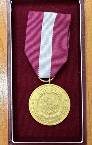 W etui jest położony medal. Po środku medalu jest orzeł i wokół niego napis: Medal za długoletnią służbę.