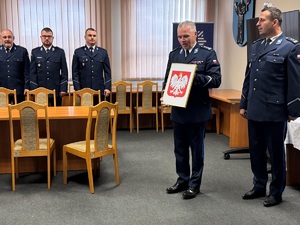 Pan komendant trzyma w rekach godło Polski. Po prawej stronie zdjęcia stoi zastępca komendanta.