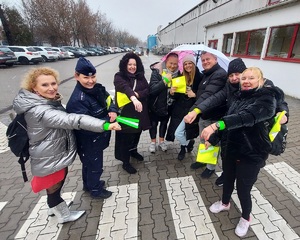 Do zdjęcia pozuje kilka osób i policjantka, wszyscy mają na nadgarstkach założone opaski odblaskowe. Wszyscy pozują do zdjęcia.