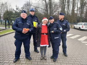 Policjanci pozują do zdjęcia razem z kobietą, która jest przebrana za Mikołaja.