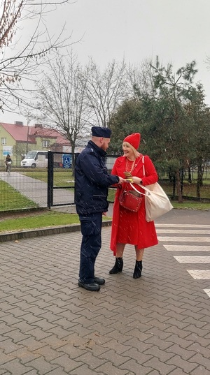 Policjant wręcza kobiecie odblask.