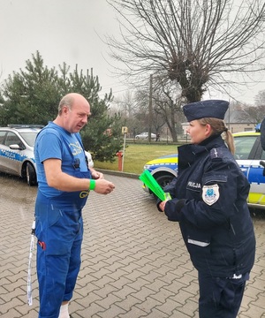 Policjantka dake mężczyźnie opaskę odblaskową. Rozmawiają.