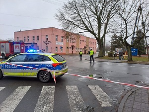 Skrzyżowanie. Stoi radiowóz, dalej dwaj policjanci, kierują objazdem. W tle widać budynek Miejskiego Domu Kultury w Zduńskiej Woli.