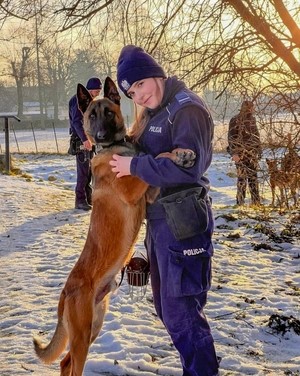 Policjanta pozuje do zdjęcia ze służbowym psem.