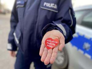 Policjant pokazuje na dłoni serduszko z napisem Wielka Orkiestra Świątecznej POmocy